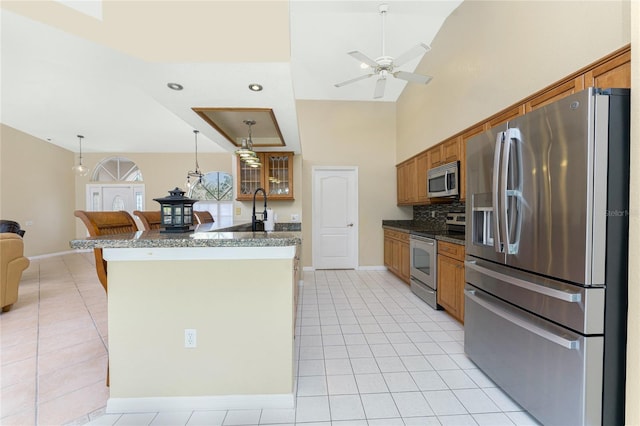 16571 Cape Horn Blvd, Punta Gorda, FL 33955 - kitchen featuring a breakfast bar area, light tile patterned floors, stainless steel appliances, dark countertops, and brown cabinets