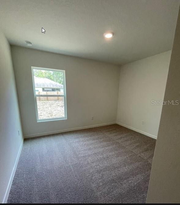 unfurnished room with carpet and baseboards