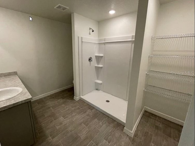 bathroom featuring a shower, wood finished floors, and vanity