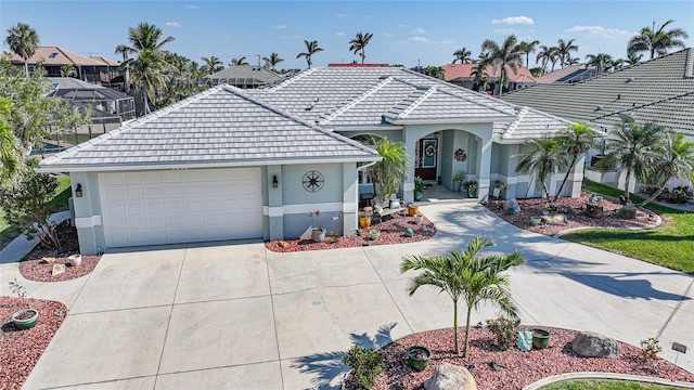 view of front of home with driveway, an attached garage, a tile roof, and stucco siding