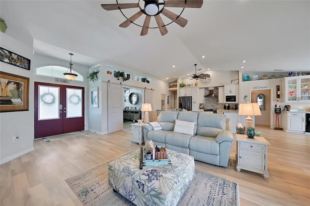 living area with french doors, lofted ceiling, recessed lighting, ceiling fan, and light wood-type flooring