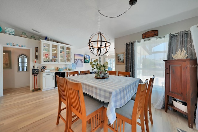 dining space with lofted ceiling, beverage cooler, visible vents, light wood-style floors, and an inviting chandelier