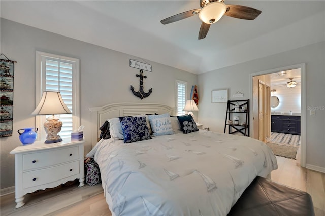 bedroom with light wood-style flooring, baseboards, ceiling fan, and connected bathroom