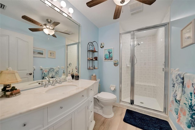 bathroom featuring visible vents, toilet, wood finished floors, vanity, and a shower stall