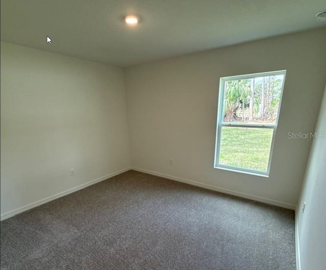 spare room featuring carpet floors and baseboards