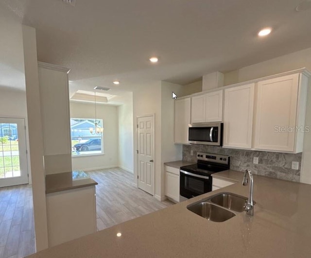 kitchen featuring range with electric stovetop, stainless steel microwave, decorative backsplash, white cabinets, and a sink