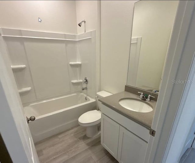 full bathroom featuring wood finished floors, tub / shower combination, vanity, and toilet