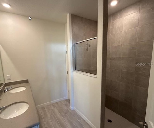 full bathroom with wood tiled floor, baseboards, walk in shower, and a sink