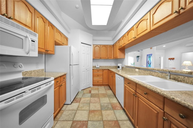 kitchen featuring brown cabinets, recessed lighting, stone finish floor, a sink, and white appliances