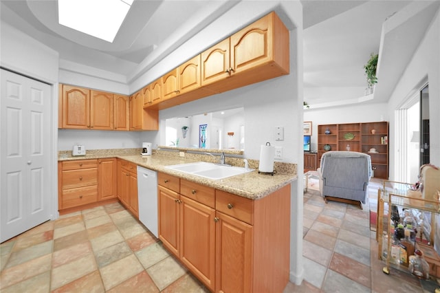 kitchen featuring a skylight, a sink, dishwasher, and light stone countertops