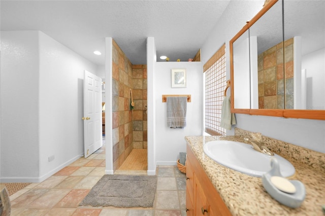 full bath with a textured ceiling, recessed lighting, vanity, baseboards, and walk in shower