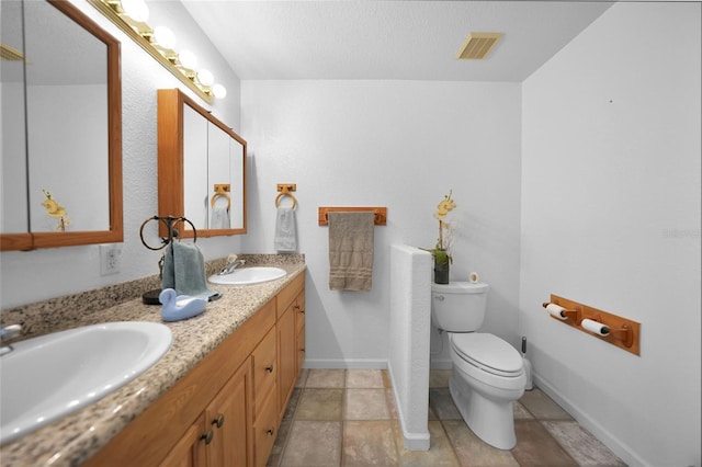 full bath featuring visible vents, a sink, toilet, and double vanity