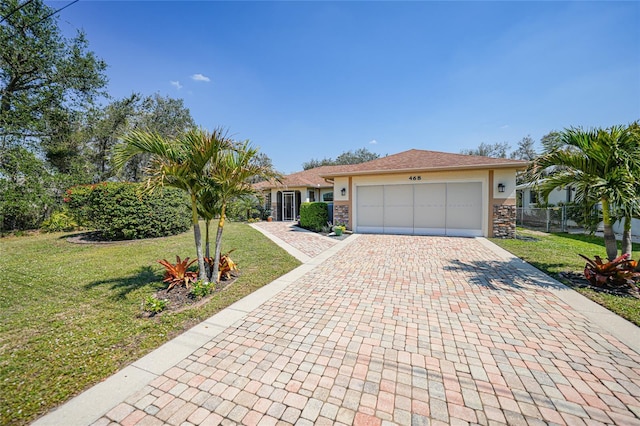 single story home featuring a garage, stone siding, decorative driveway, and a front yard