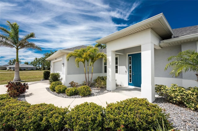 view of exterior entry with a garage and stucco siding