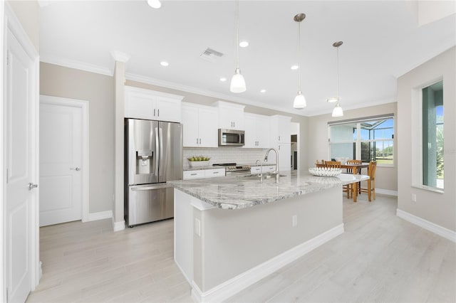 kitchen featuring visible vents, white cabinets, decorative backsplash, appliances with stainless steel finishes, and a sink