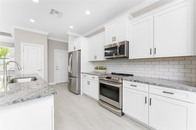 kitchen with crown molding, stainless steel appliances, tasteful backsplash, white cabinets, and a sink