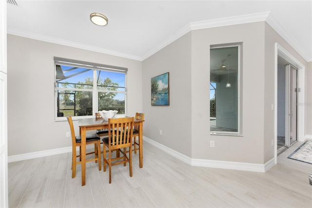 dining room with light wood finished floors, baseboards, and ornamental molding