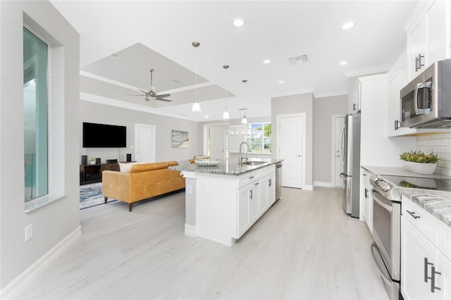 kitchen with a sink, visible vents, white cabinets, appliances with stainless steel finishes, and decorative backsplash