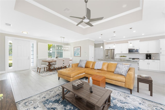 living room featuring crown molding, visible vents, and a tray ceiling