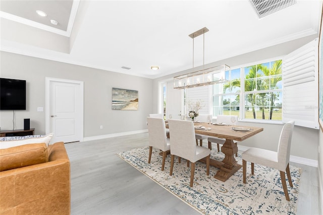 dining room with visible vents, crown molding, baseboards, and wood finished floors