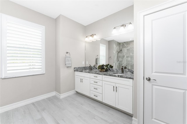 full bath with a wealth of natural light, tiled shower, a sink, and baseboards