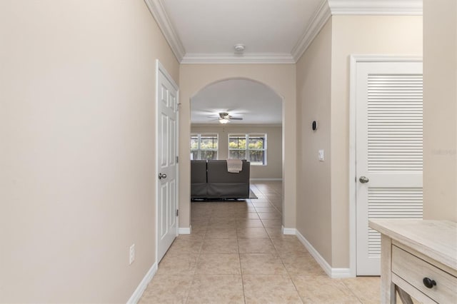 hallway with light tile patterned floors, baseboards, arched walkways, and crown molding