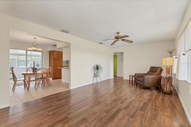 sitting room featuring light wood finished floors, baseboards, visible vents, and a textured ceiling