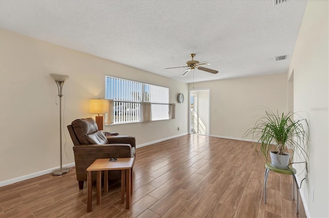 sitting room with visible vents, a ceiling fan, a textured ceiling, wood finished floors, and baseboards
