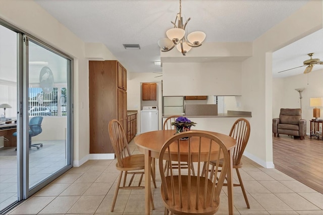 dining space with light tile patterned floors, a textured ceiling, visible vents, baseboards, and washer / clothes dryer