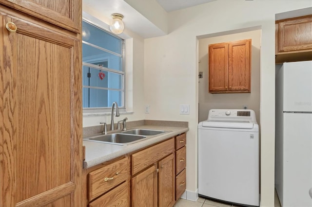laundry area featuring light tile patterned flooring, cabinet space, a sink, and washer / dryer