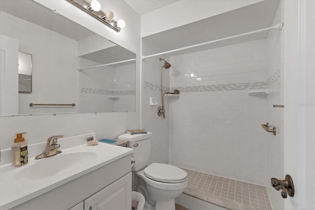 bathroom with vanity, a tile shower, and toilet