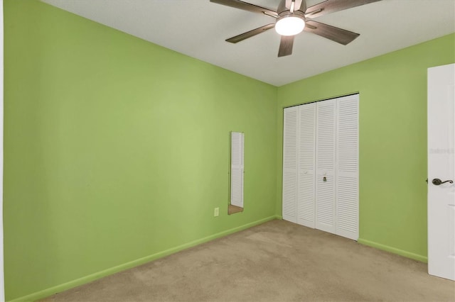 unfurnished bedroom featuring light carpet, ceiling fan, baseboards, and a closet