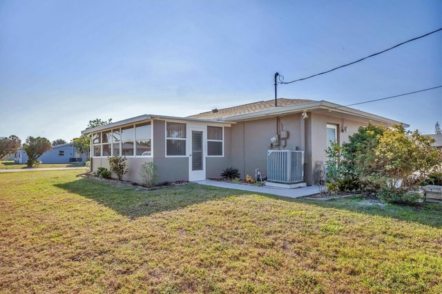 rear view of property featuring a yard, stucco siding, and central air condition unit
