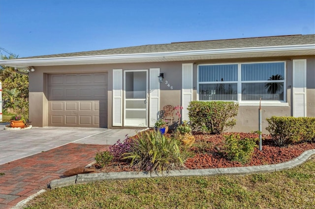 view of front of property with driveway, roof with shingles, a garage, and stucco siding