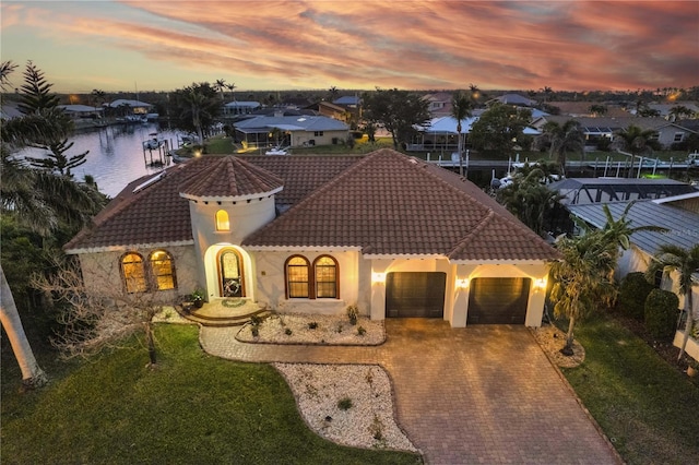 mediterranean / spanish-style house with stucco siding, a front lawn, a tile roof, decorative driveway, and an attached garage