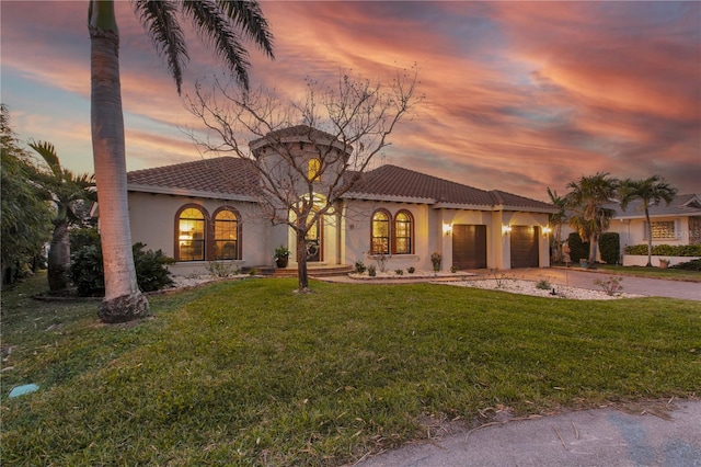 mediterranean / spanish-style house with a lawn, concrete driveway, an attached garage, and a tile roof