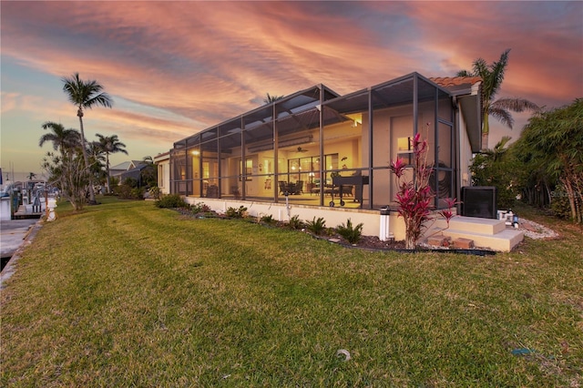 rear view of property featuring a lanai and a lawn