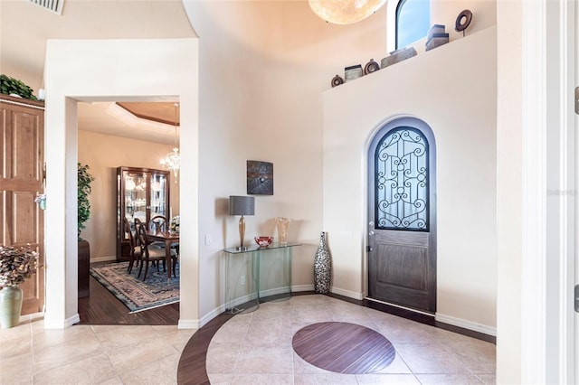 foyer entrance with light tile patterned flooring, baseboards, and a tray ceiling