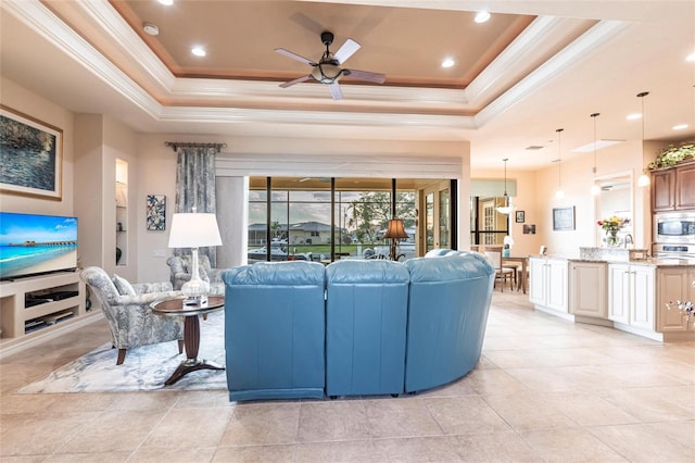 living room featuring built in features, a tray ceiling, recessed lighting, ceiling fan, and crown molding