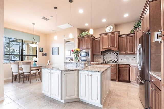 kitchen with visible vents, a center island with sink, stainless steel appliances, decorative backsplash, and light stone countertops