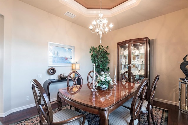 dining room with dark wood-style floors, visible vents, baseboards, a raised ceiling, and a notable chandelier