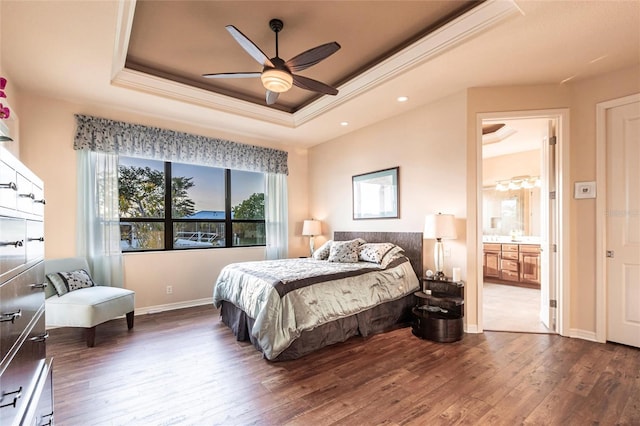 bedroom with a raised ceiling, ornamental molding, ensuite bath, wood finished floors, and baseboards