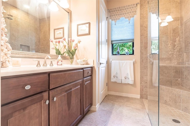 full bath featuring tile patterned flooring, baseboards, vanity, and a walk in shower