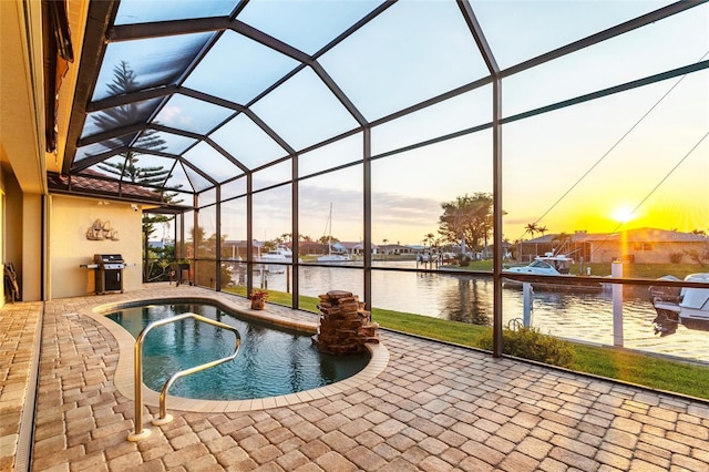 pool at dusk with glass enclosure, a water view, and a patio area