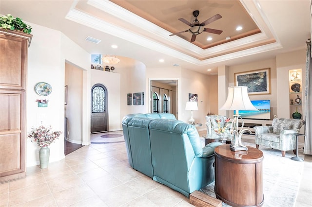 living area featuring light tile patterned floors, visible vents, a raised ceiling, and ornamental molding