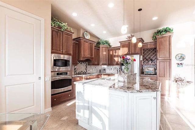 kitchen featuring a sink, appliances with stainless steel finishes, decorative backsplash, light stone countertops, and hanging light fixtures