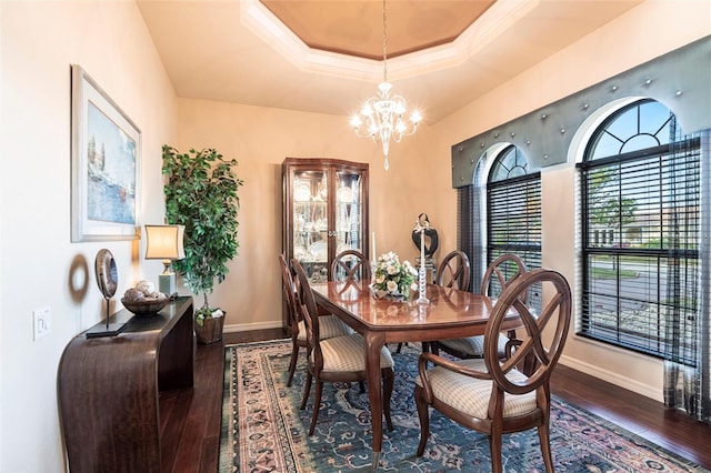 dining space featuring a tray ceiling, a notable chandelier, dark wood-style floors, and baseboards