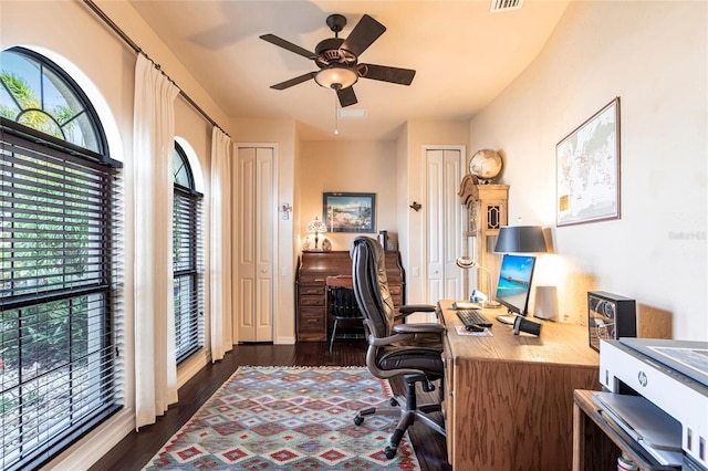 home office featuring visible vents, plenty of natural light, ceiling fan, and dark wood-style flooring