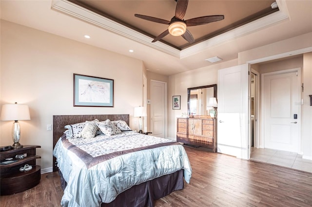 bedroom with wood finished floors, baseboards, a tray ceiling, recessed lighting, and ornamental molding