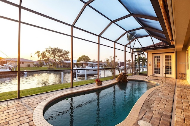 pool with glass enclosure, a patio, french doors, and a water view